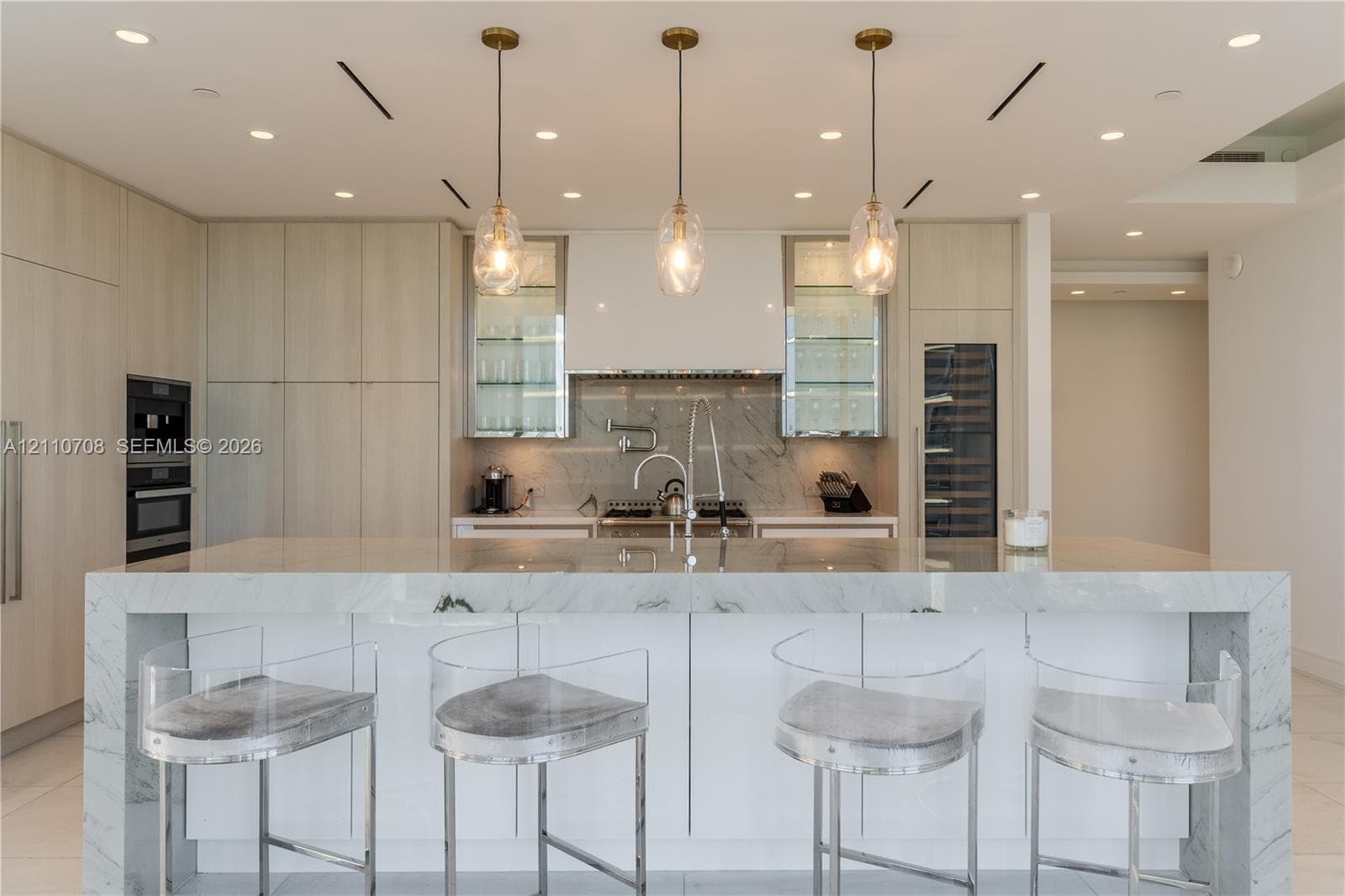 Textured ceiling paneling with integrated recessed lighting, custom floating cabinetry, and decorative accent wall surfacing