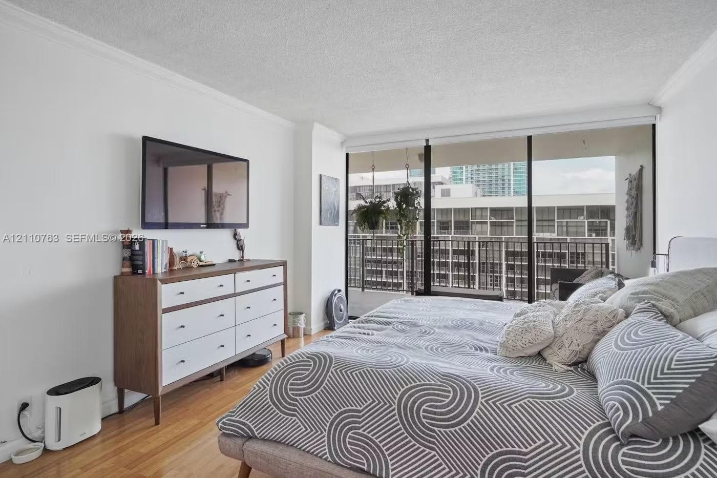 Floor-to-ceiling windows featuring access to a private balcony, wood-finish flooring, and crown molding