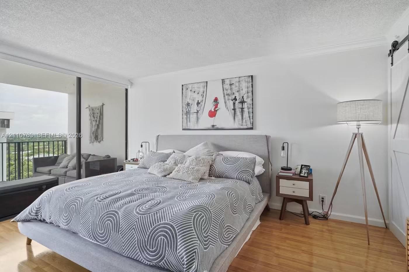 Wood-finish flooring, floor-to-ceiling glass sliding doors, private balcony, and white sliding barn door