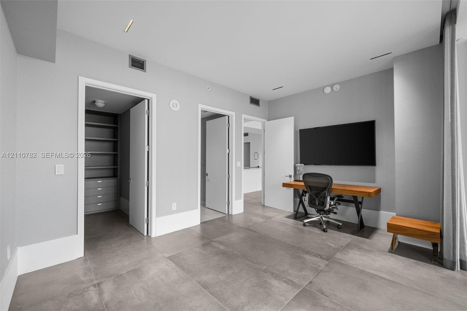 Custom organizational system featuring floor-to-ceiling cabinetry, integrated shelving, hanging rods, and built-in drawers with metallic hardware, set against tiled flooring