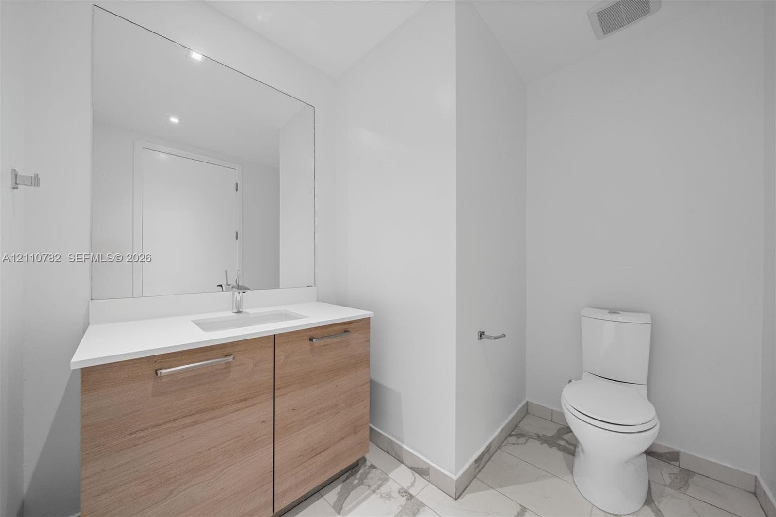Utility area featuring stone-surface countertop, built-in cabinetry, large-format tile flooring, and dedicated laundry closet with stacked appliance configuration
