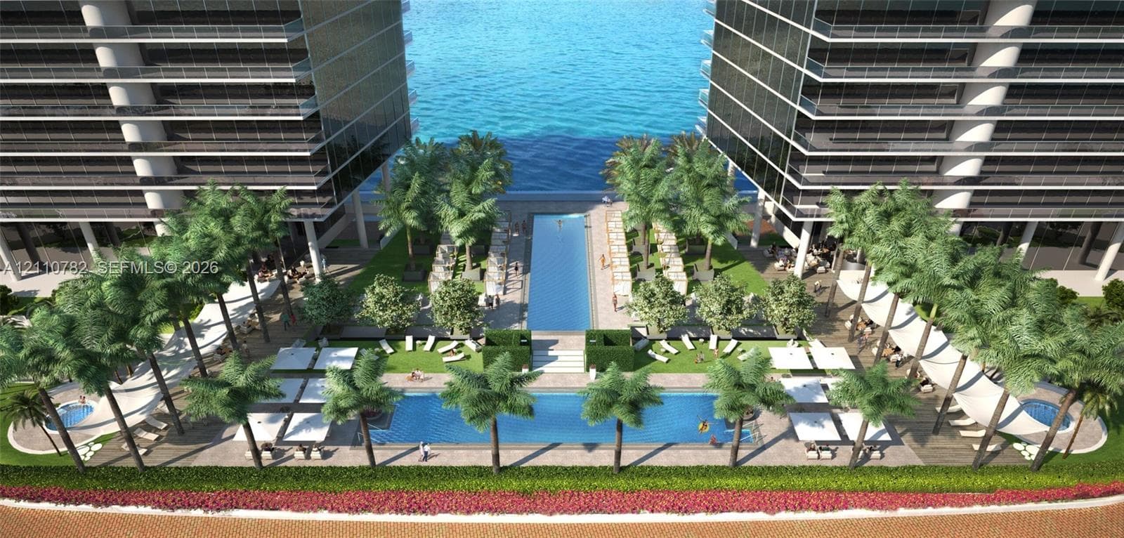 High-rise structure featuring stacked glass-railing balconies, situated on a waterfront lot with manicured lawn, mature palm trees, and direct bulkhead water frontage