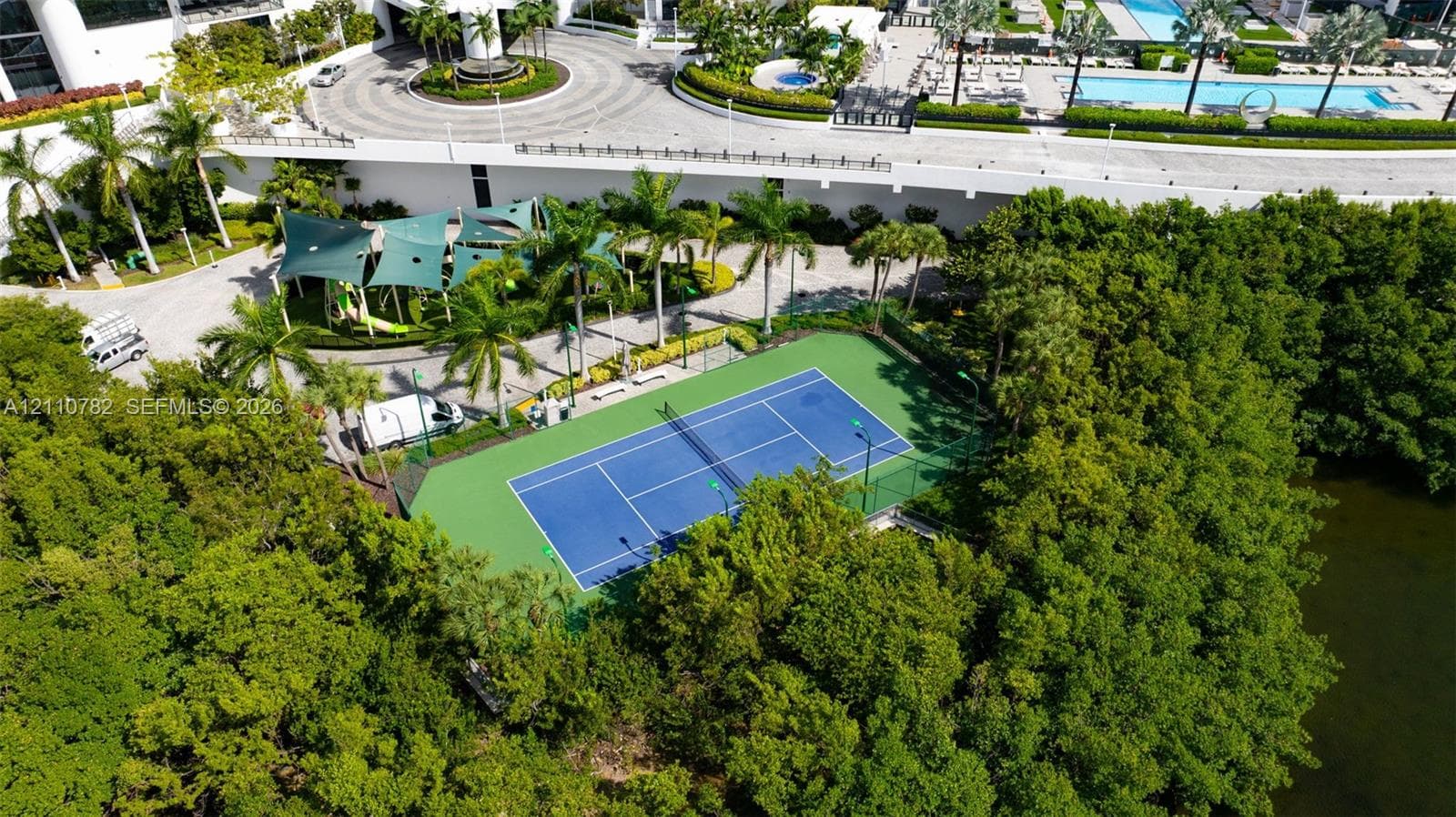 High-rise residential exterior featuring stacked private balconies, waterfront grounds with palm trees, and direct access to a private dock facility