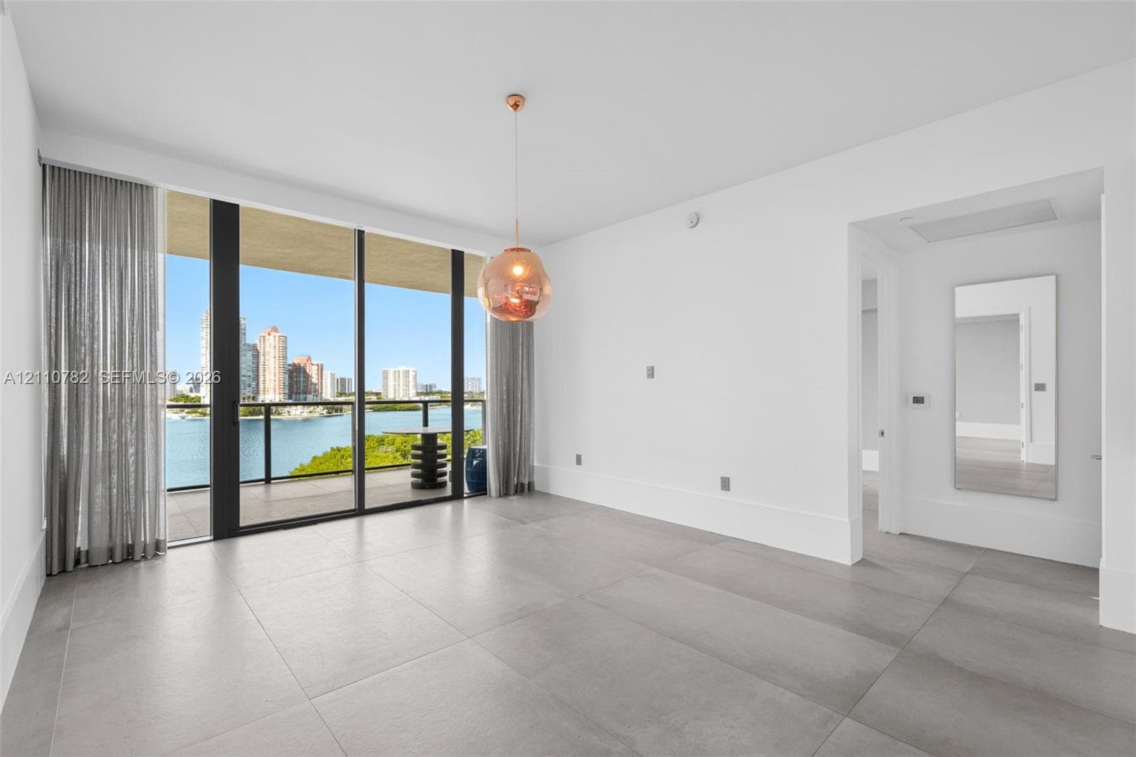 Open-concept space featuring large-format ceramic tile flooring, floor-to-ceiling windows, integrated stainless steel kitchen cabinetry, and recessed ceiling lighting