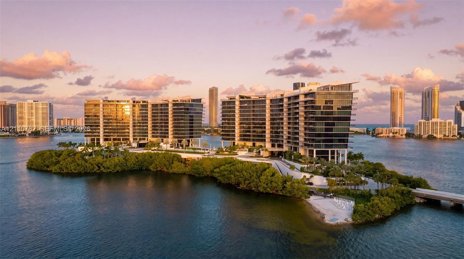 Multi-story waterfront high-rise featuring floor-to-ceiling glass windows, expansive private terraces, and extensive grounds with tropical landscaping