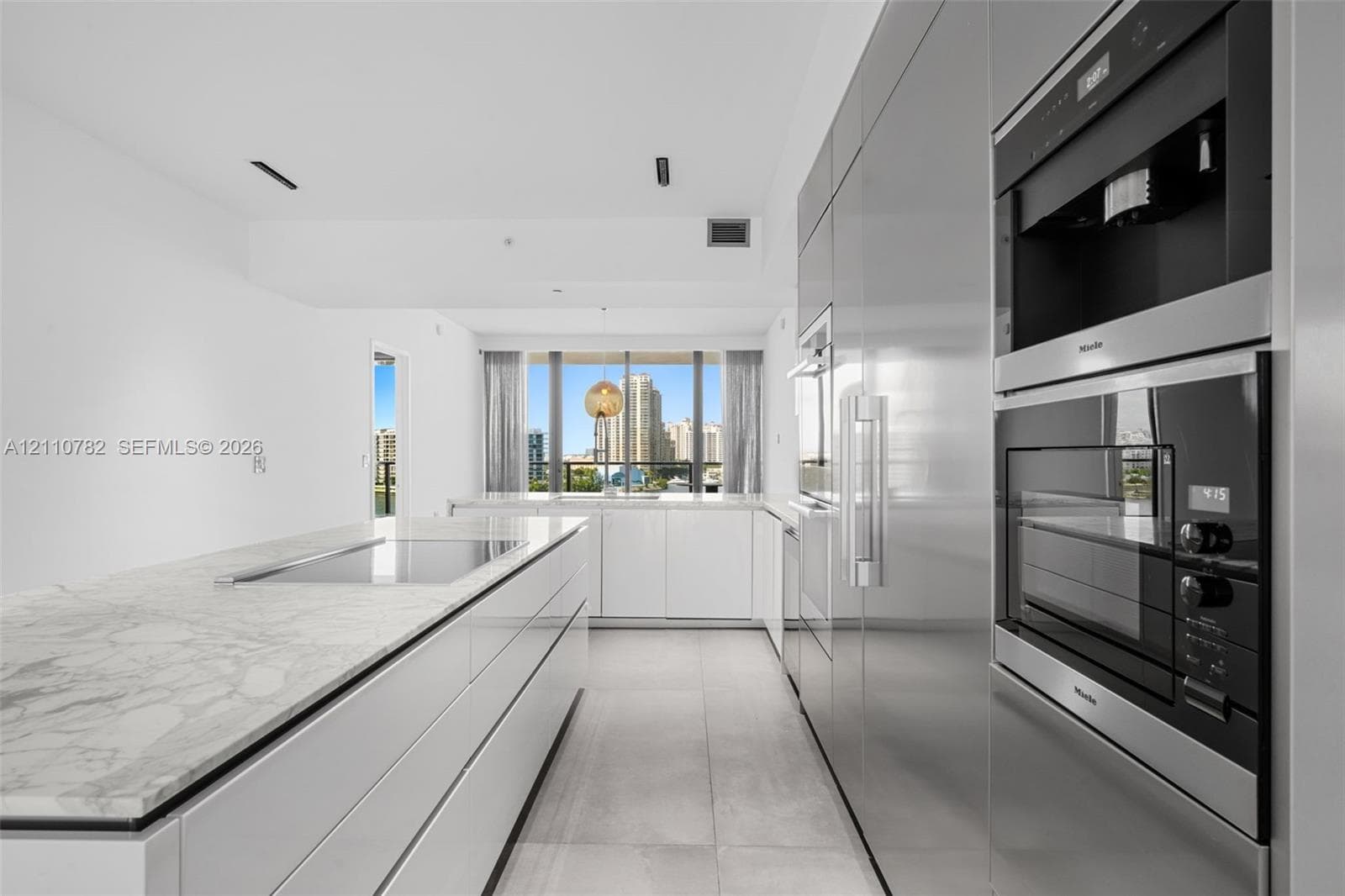 Contemporary kitchen featuring an expansive center island with stone surfacing, stainless steel built-in appliances, flat-panel cabinetry, a stone backsplash, and large-format floor tiling