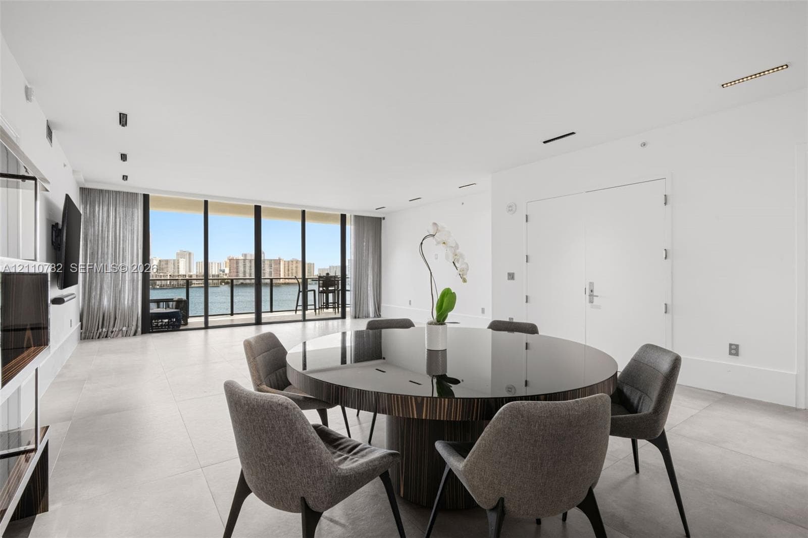 Waterfront high-rise building situated on a private peninsula, featuring wraparound balconies, an outdoor swimming pool, lush landscaping, and direct access via a private bridge
