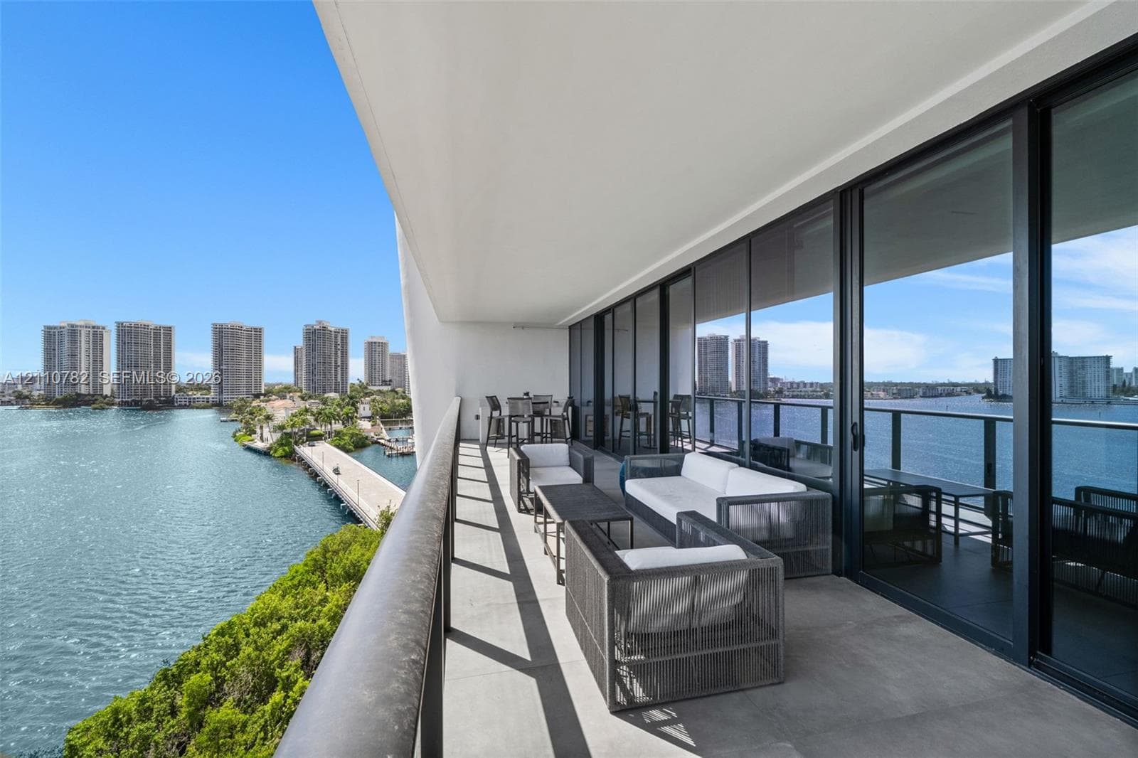 Expansive covered balcony featuring large-format porcelain tile flooring and a black metal railing with glass inserts
