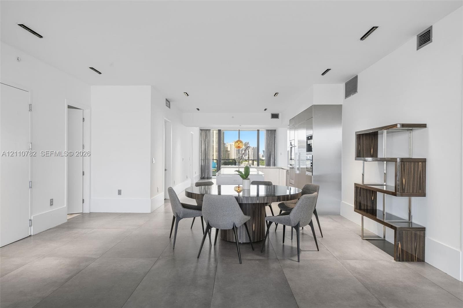 Entry foyer featuring large-format grey tile flooring, minimalist white walls, recessed ceiling lighting, and a matte black elevator entrance