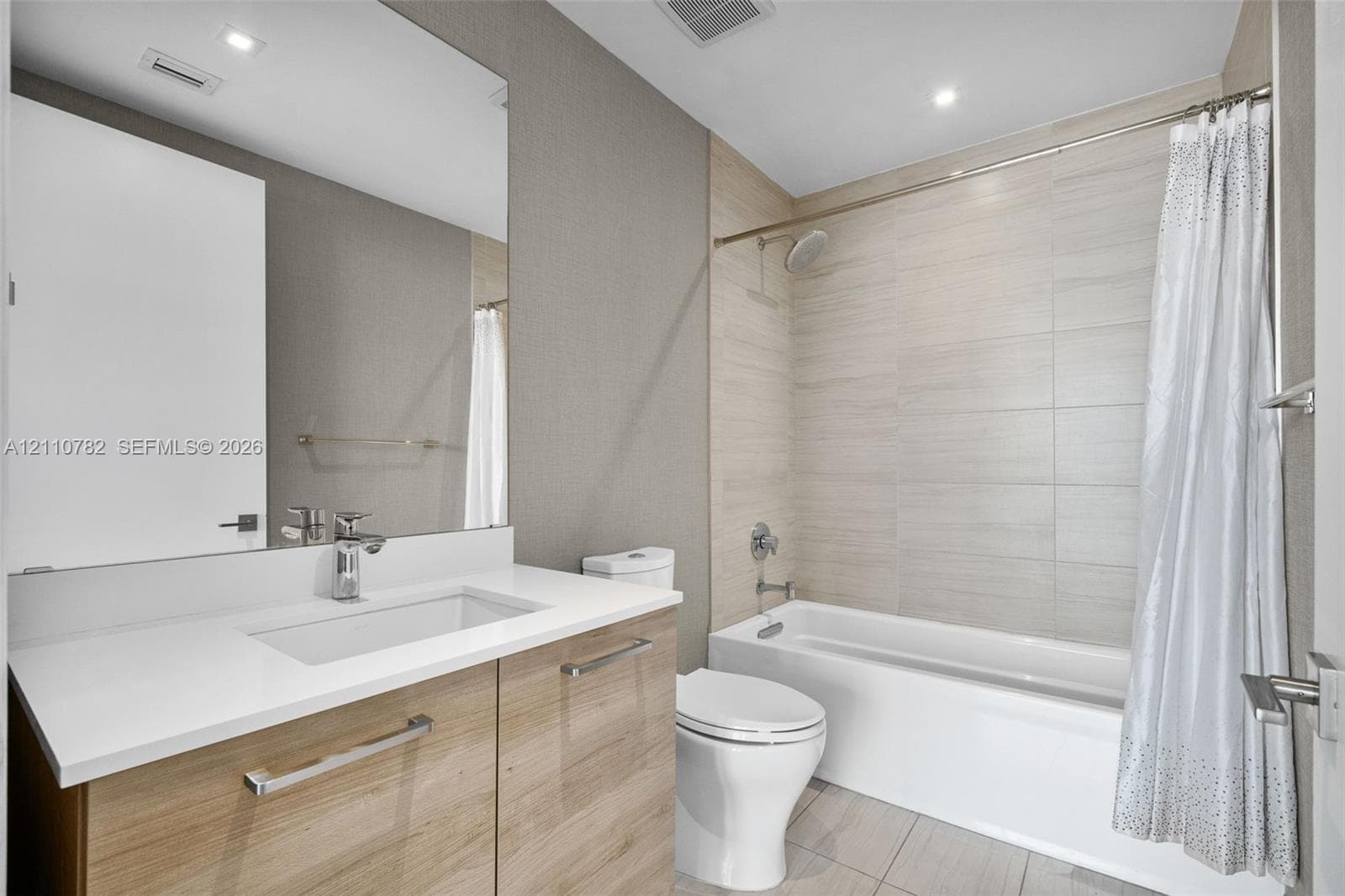 Floor-to-ceiling glass wall, large-format tile flooring, recessed ceiling lighting, and covered balcony featuring a glass panel railing
