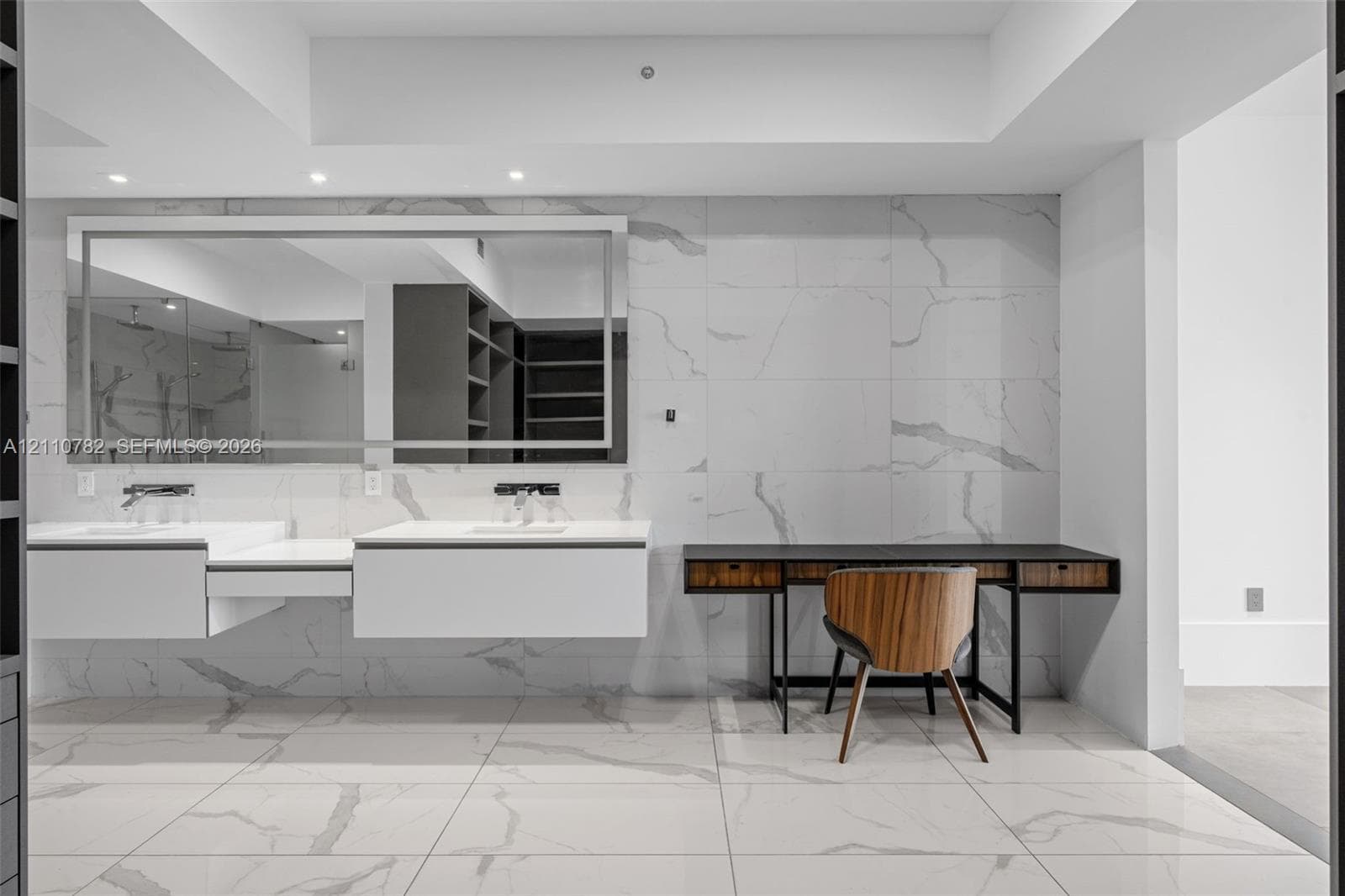 Custom built-in storage system with grey cabinetry, large-format tiled flooring, wall-to-wall vanity with dual sinks, and full-height tiled wall detailing
