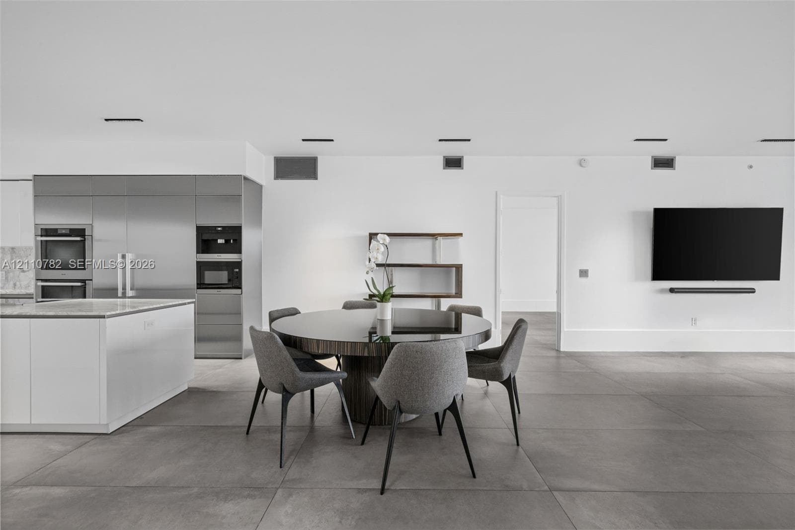 Open-concept interior featuring large-format tile flooring, floor-to-ceiling glass panel windows, integrated recessed lighting, and a private balcony