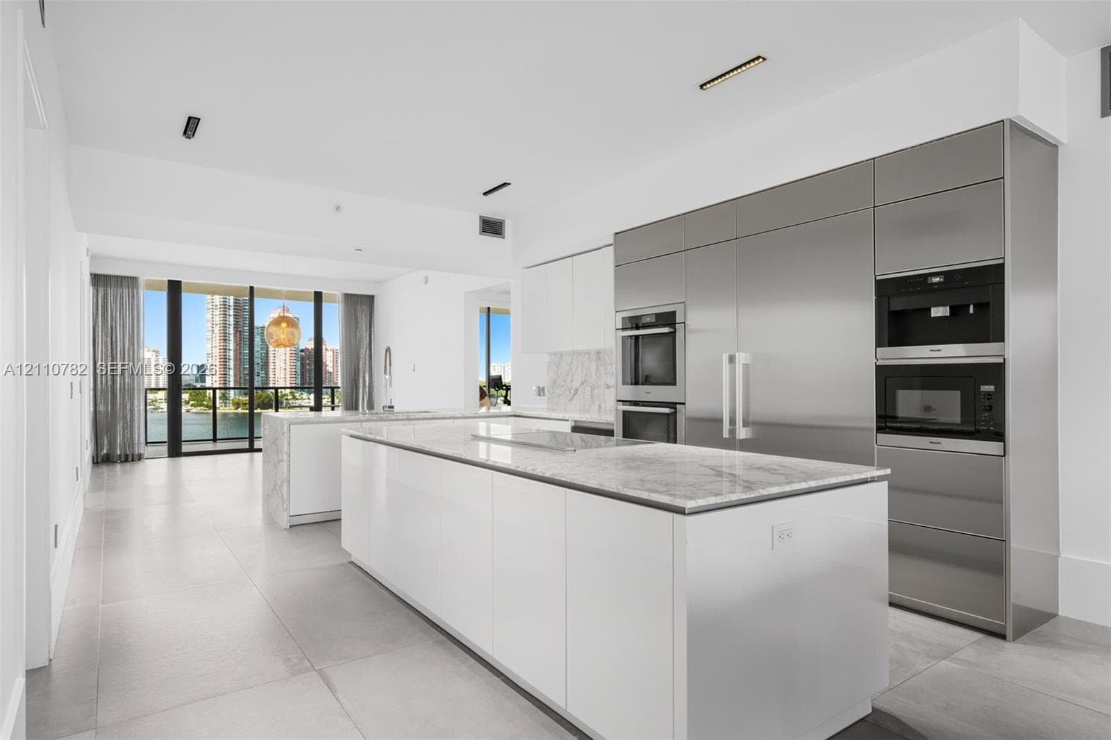 Open concept interior featuring large-format grey tile flooring, recessed ceiling lighting, and a neutral white color palette