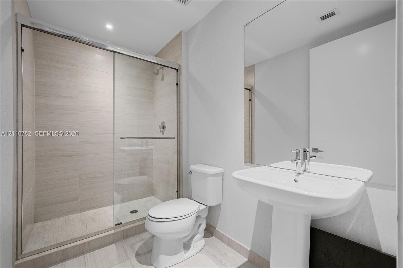 Interior room featuring large-format grey tile flooring, neutral wall tones, recessed linear ceiling lighting, and solid-core interior doors