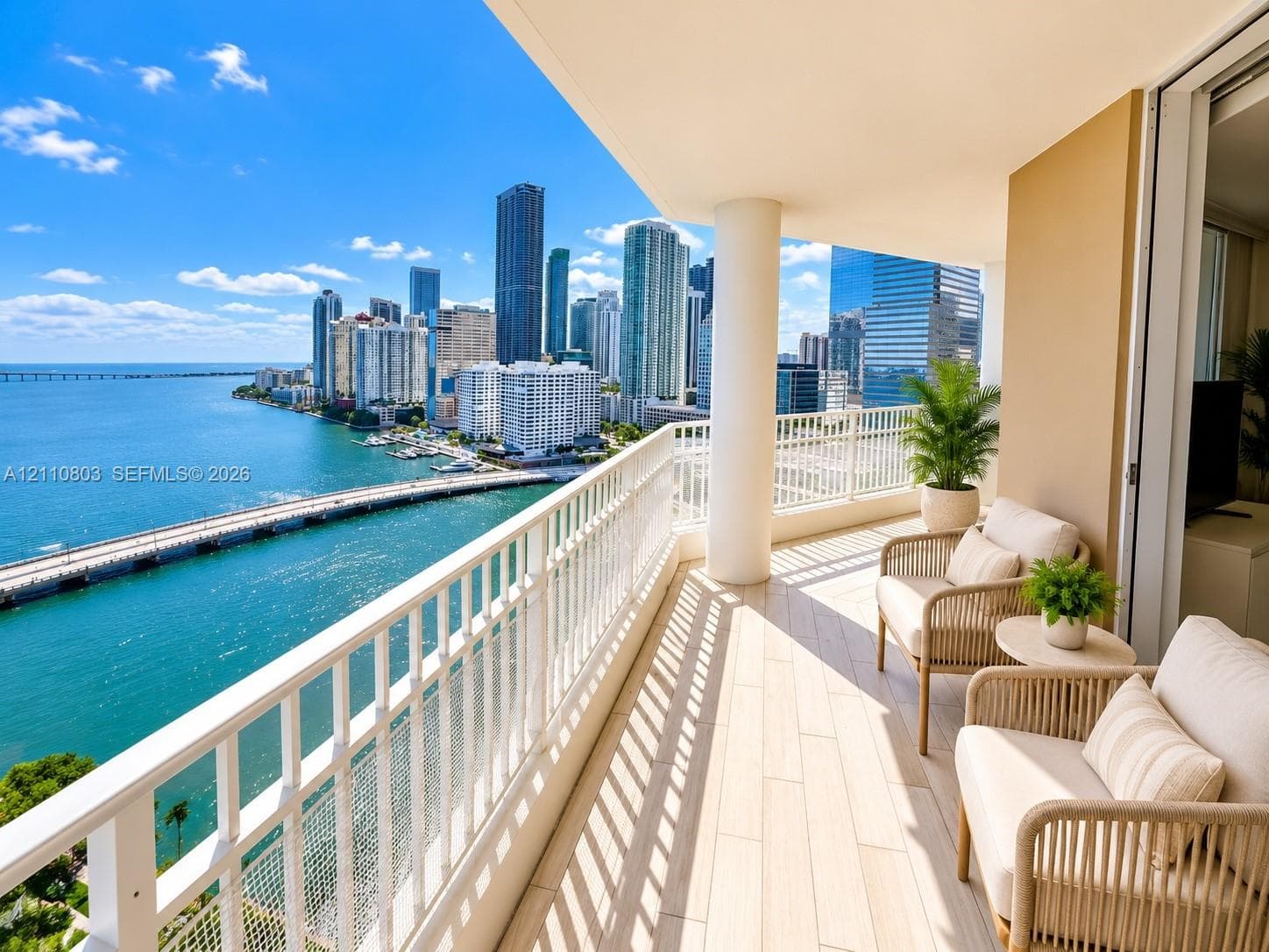 Covered balcony featuring wood-finish tile flooring, white metal railing, and expansive cityscape and water scenery