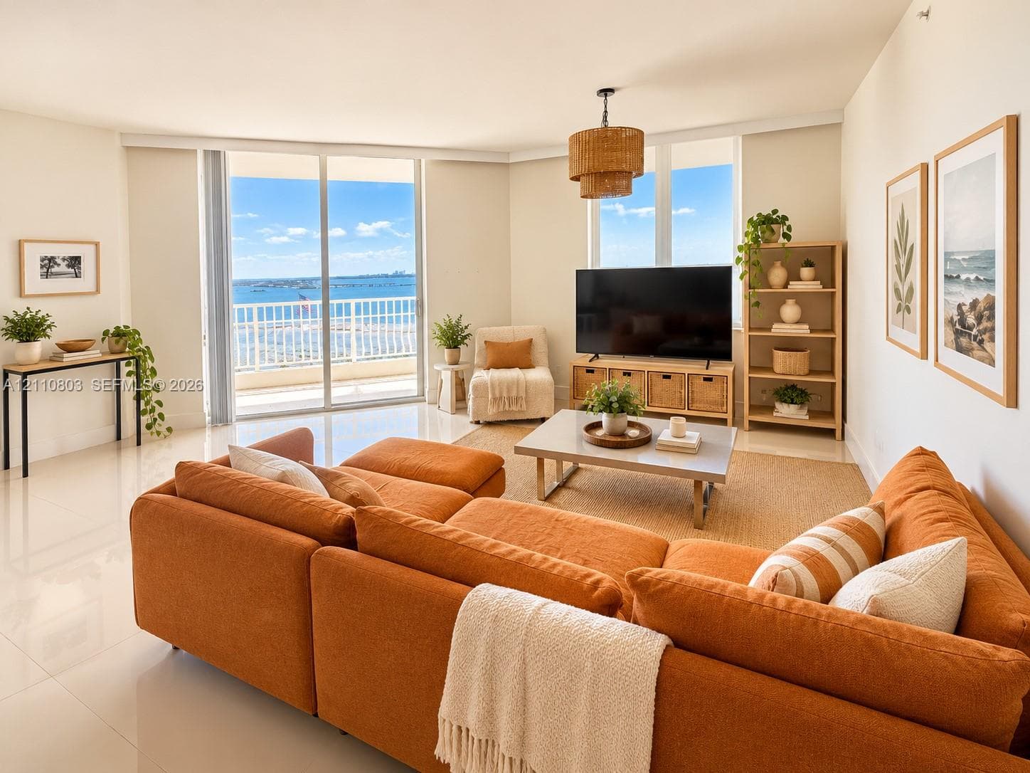 Open-concept living space featuring high-gloss tile flooring, floor-to-ceiling sliding glass doors, a private balcony with metal railing, and expansive windows