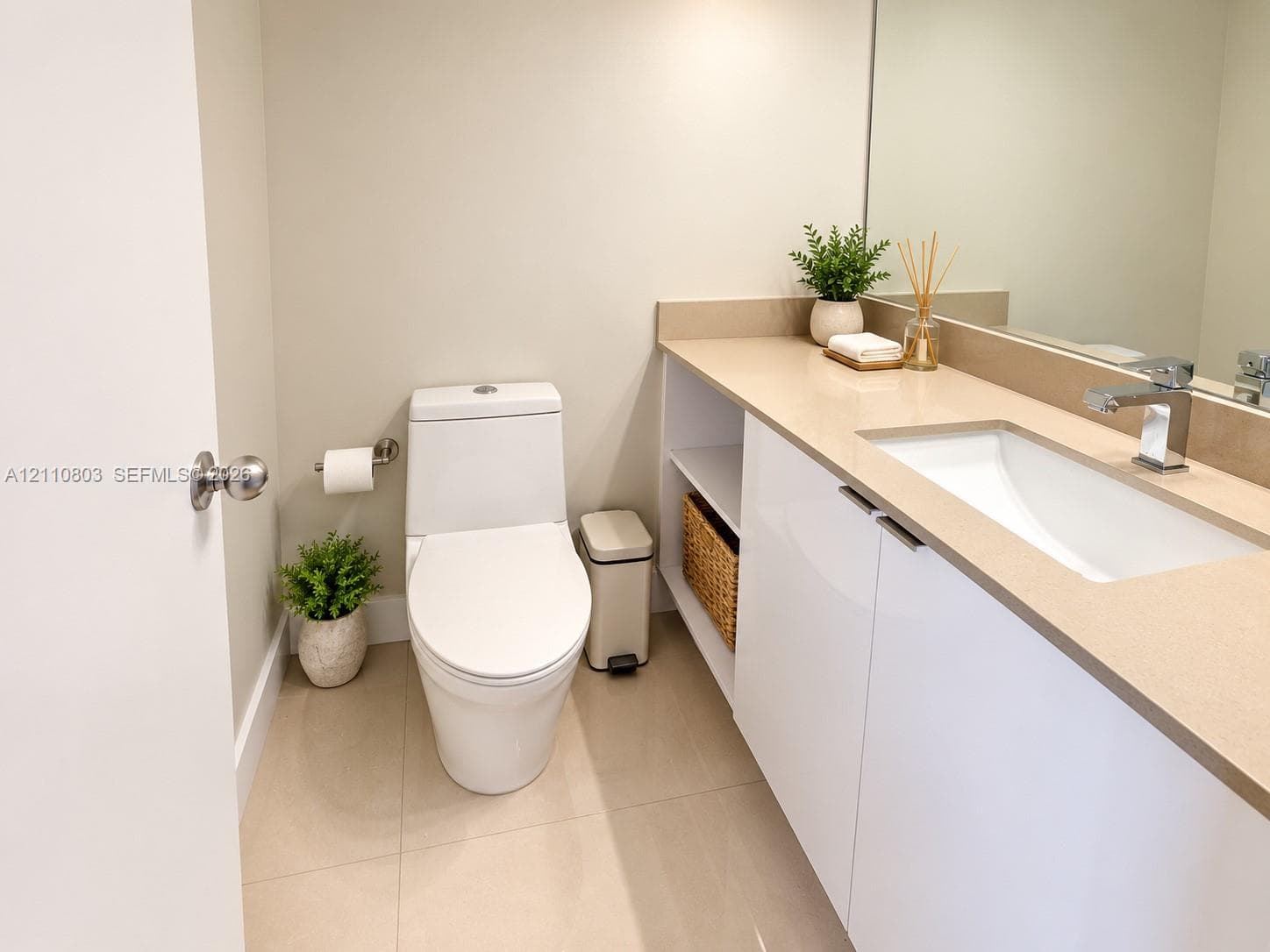Modern vanity featuring a sleek countertop with an integrated rectangular basin, minimalist cabinetry with open shelving, a wall-to-wall mirror, and a one-piece toilet