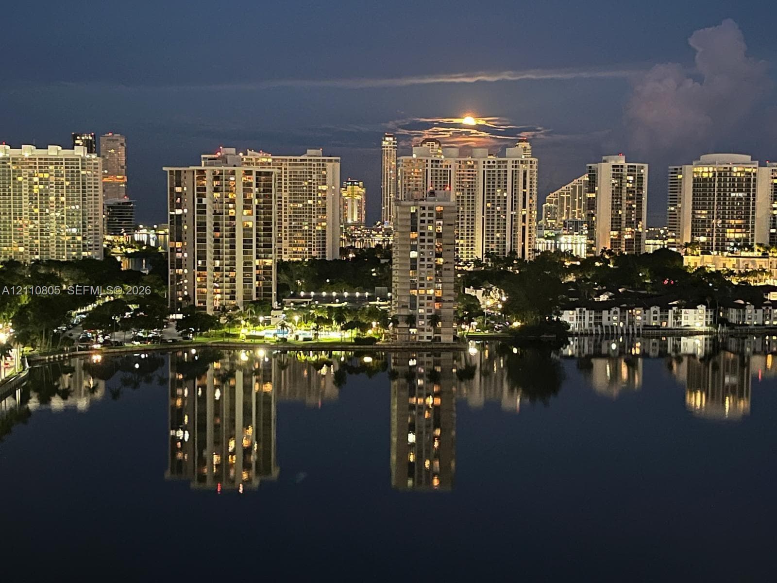 Panoramic cityscape featuring high-rise architecture, expansive water frontage, and reflections across the water surface