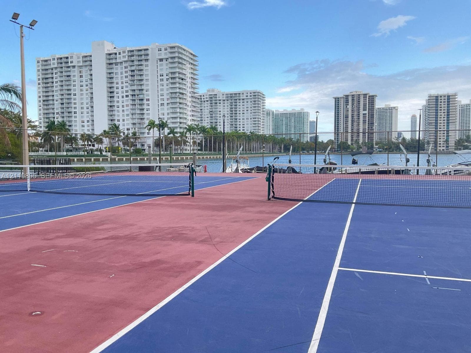 Multi-court tennis facility featuring high-tension netting, perimeter fencing, and pole-mounted floodlighting