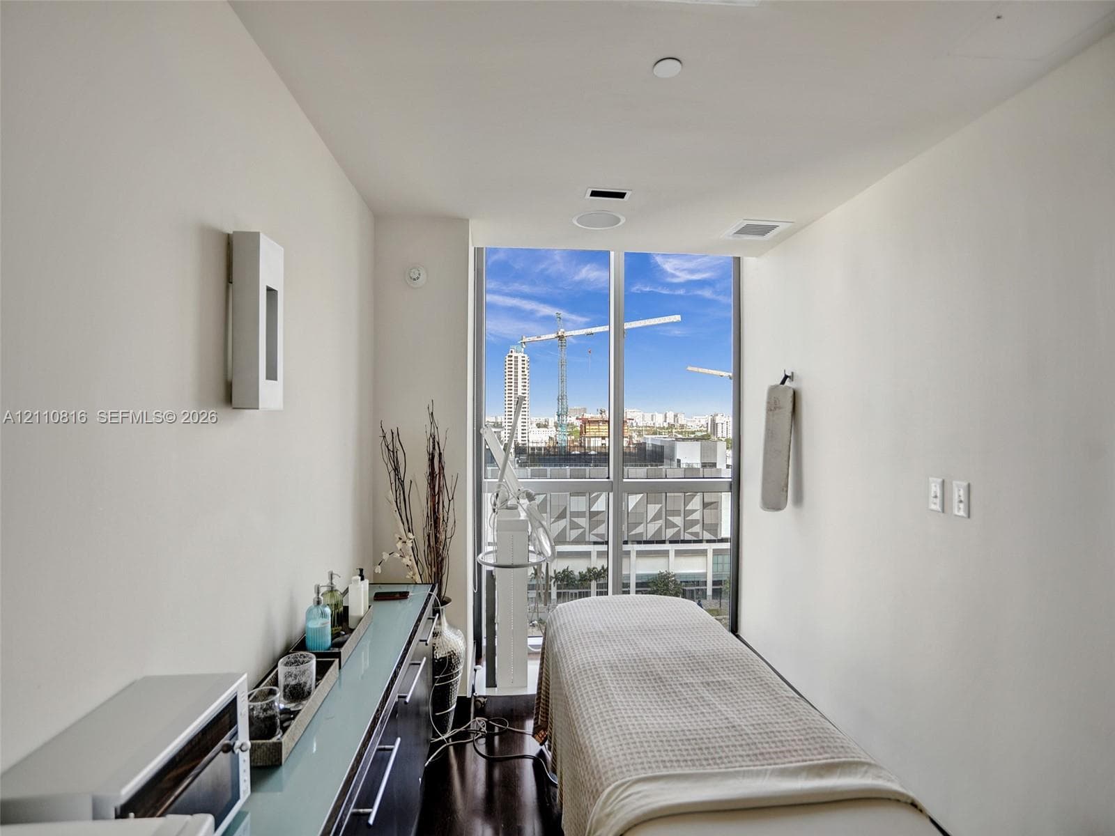 Floor-to-ceiling windows, dark wood-finish flooring, built-in cabinetry with a glass surface, recessed ceiling lighting, and wall-mounted sconce lighting