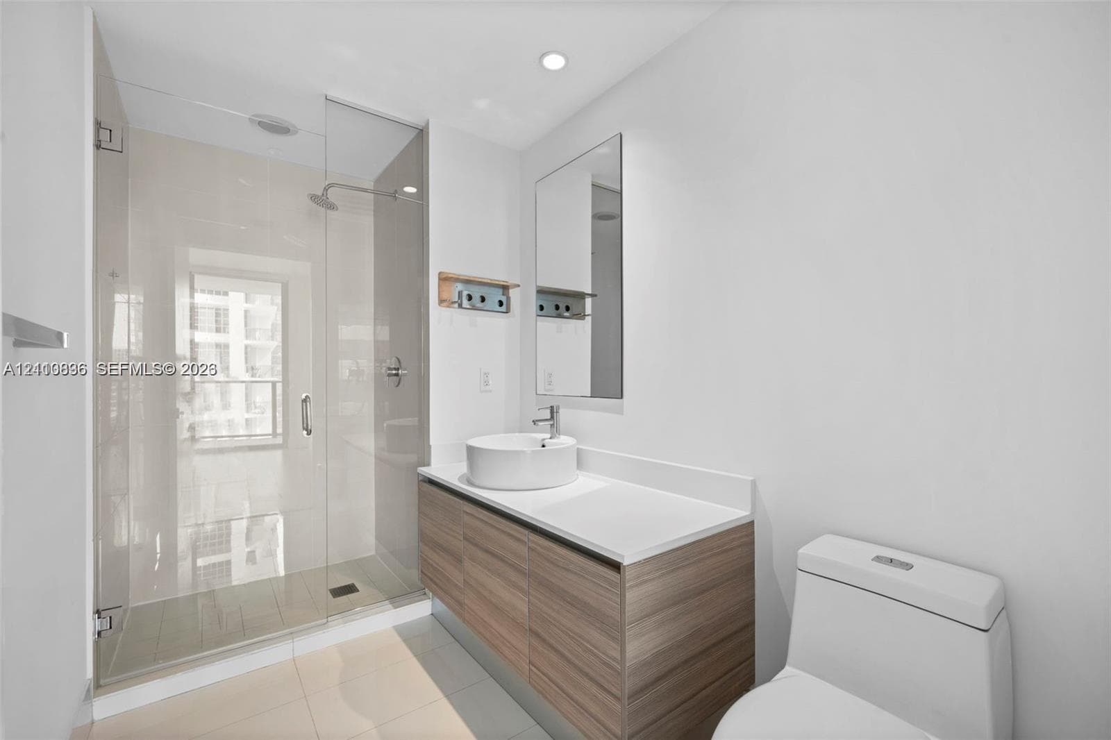 Bathroom featuring a wood-finish floating vanity, circular vessel sink, white solid-surface countertop, and a walk-in glass-enclosed shower with polished chrome fixtures