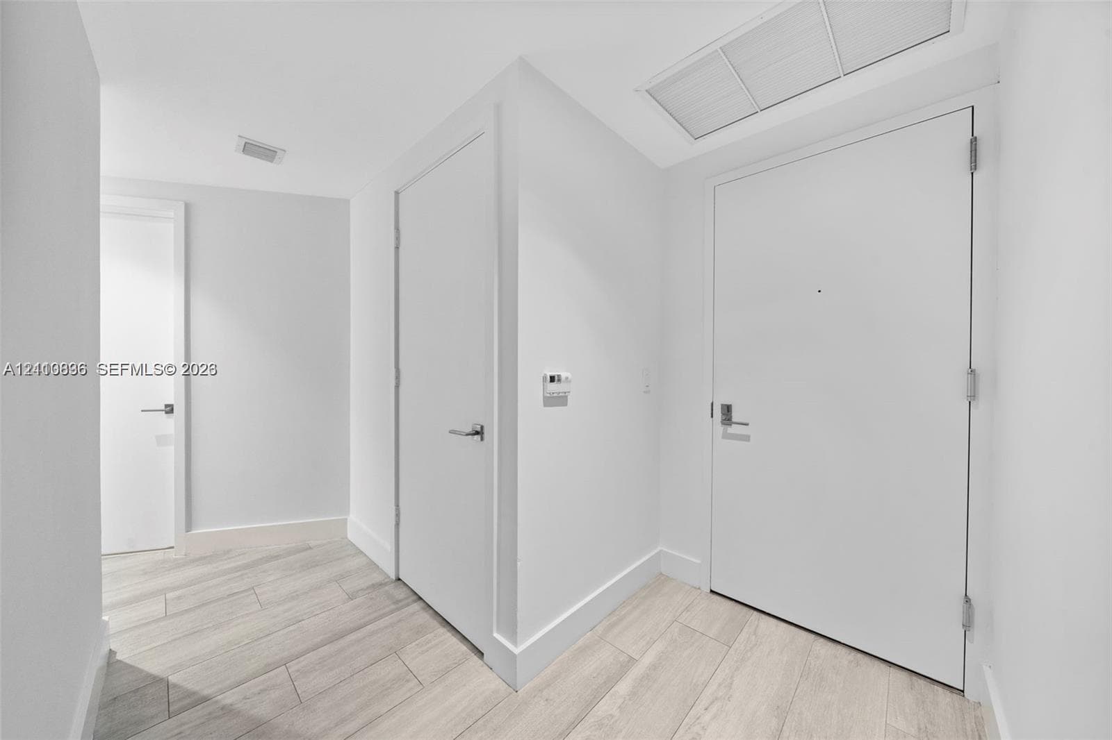 Interior space featuring neutral wall paint, wood-finish flooring, solid-core doors with satin-finish hardware, and recessed ceiling lighting
