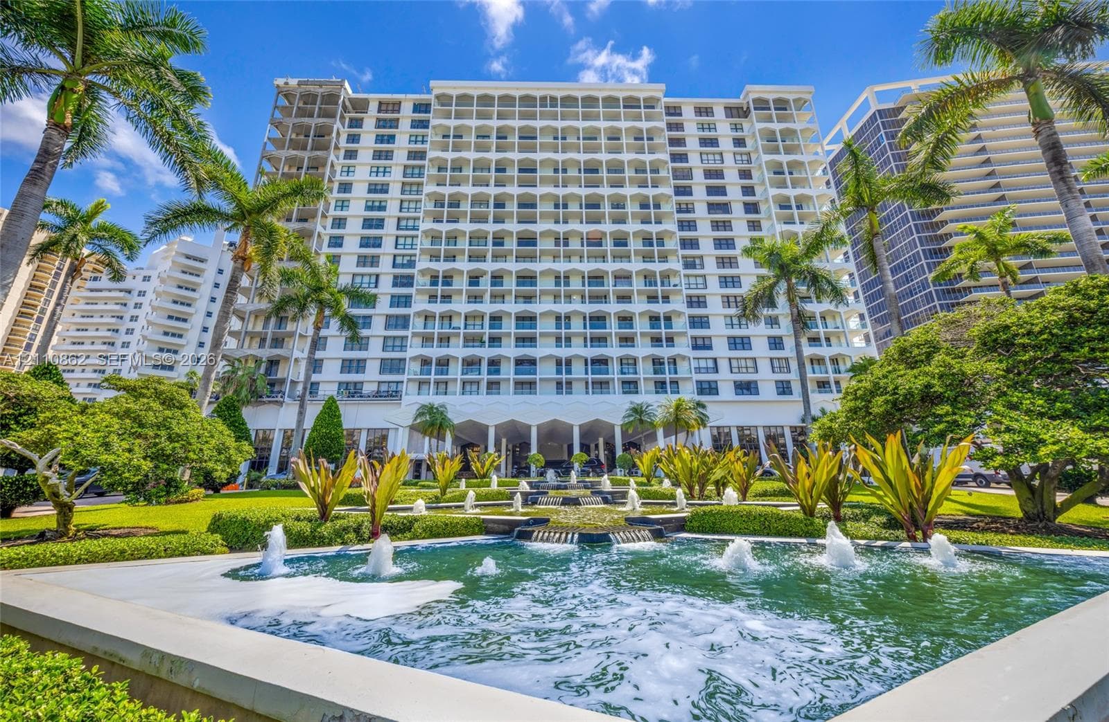 Balmoral residential exterior featuring a multi-tiered fountain, manicured lawn, established landscaping, and palm trees