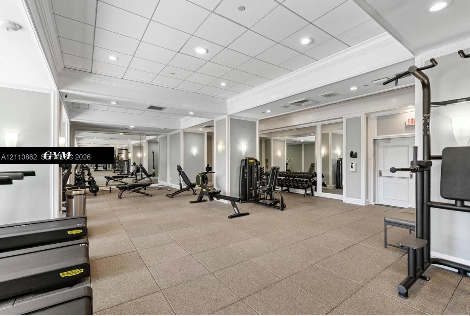 Fitness area featuring high ceilings with recessed lighting, mirrored wall accents, crown molding, and rubberized tile flooring