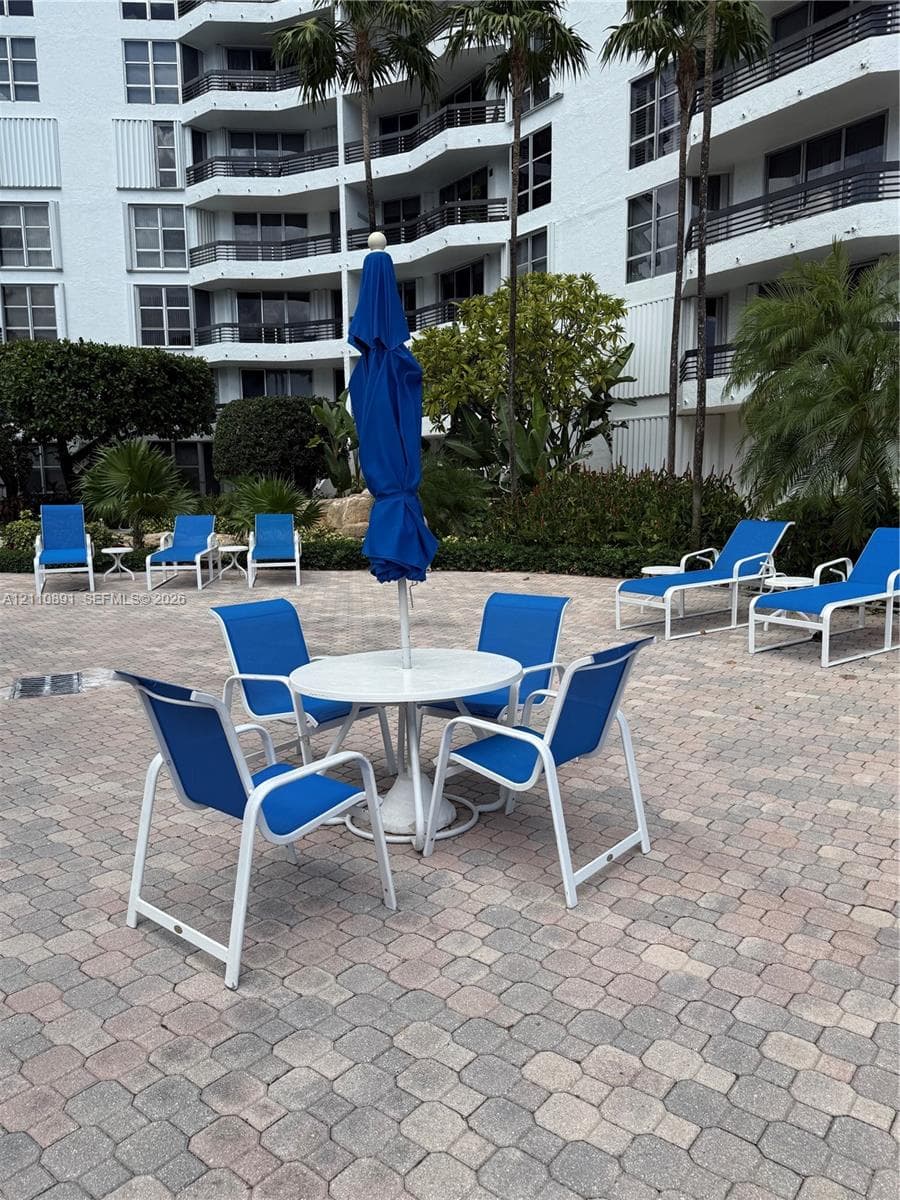 Paver patio featuring integrated landscaping, palm trees, and multi-story building exterior