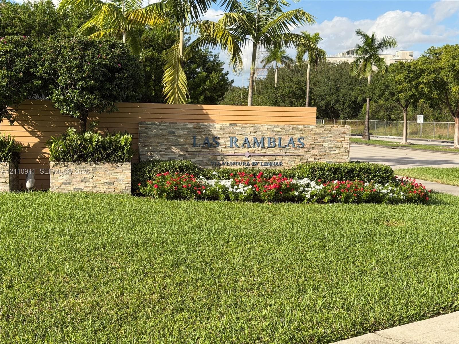 Stacked stone monument sign with dimensional lettering, set against landscaped shrubbery and a manicured lawn