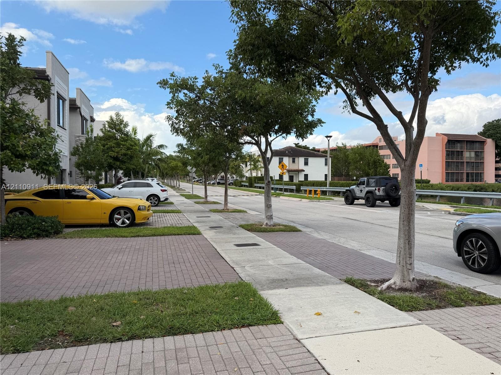 Expansive grass lawn featuring mature trees and concrete sidewalks