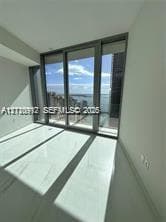 Floor-to-ceiling glass sliding doors, large-format tile flooring, and metal-framed windows featuring coastal scenery