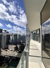 Covered balcony featuring glass paneled railings, concrete flooring, and floor-to-ceiling glass wall enclosures