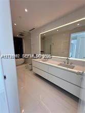 Floating dual-sink vanity with matte finishes, quartz countertop, large backlit mirror, and freestanding soaking tub