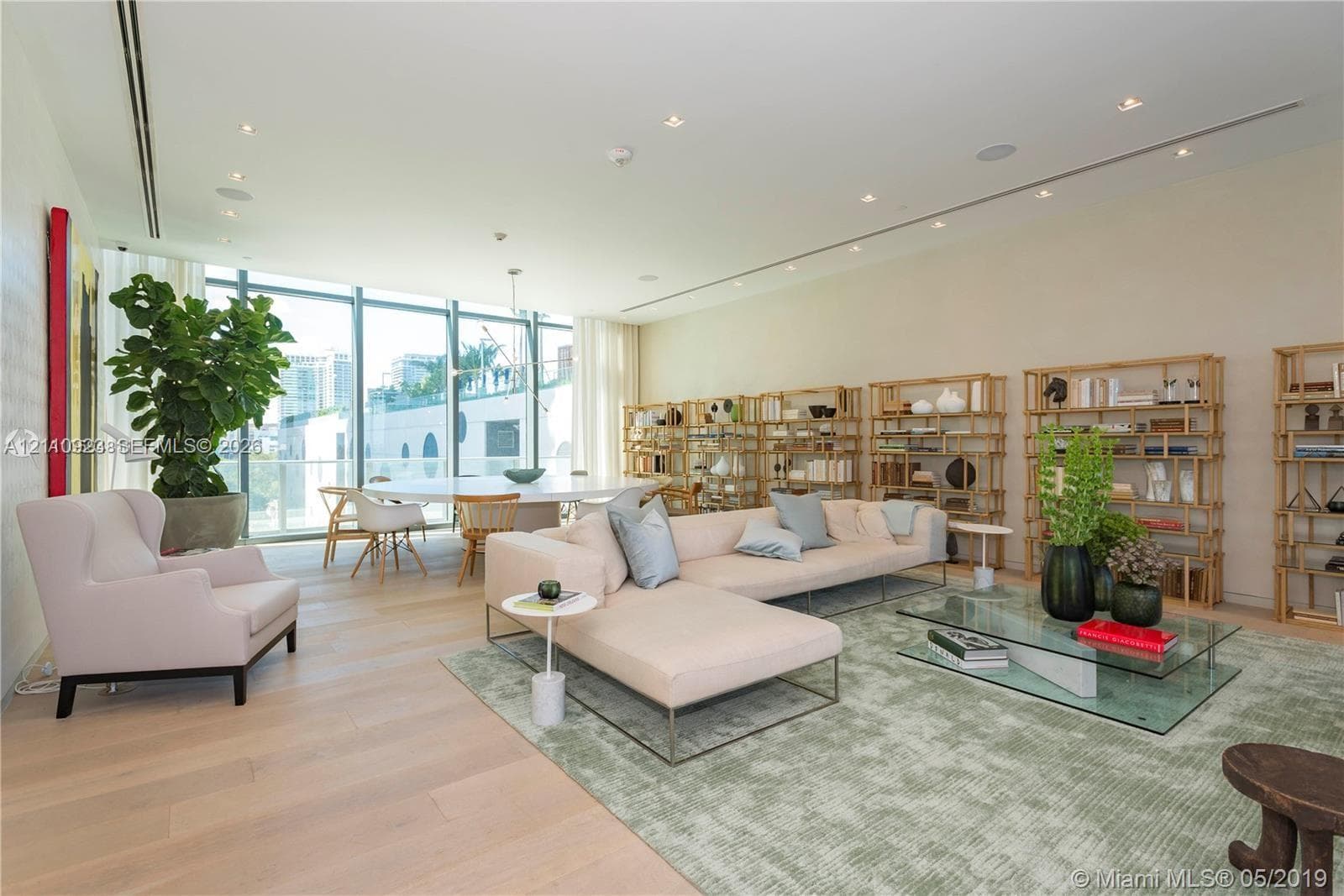 Open-concept living space featuring floor-to-ceiling windows, wide-plank wood-finish flooring, recessed lighting, and built-in shelving