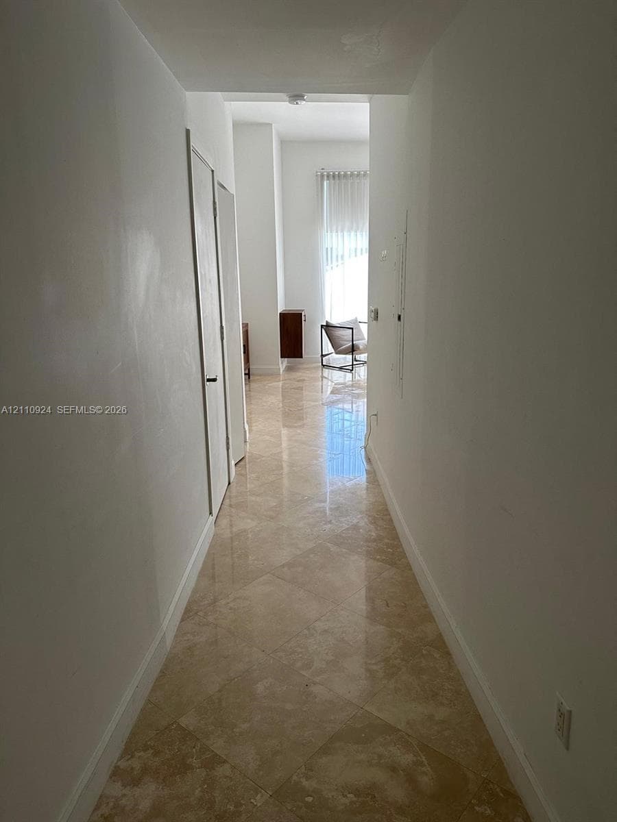 Polished stone flooring laid in a diamond pattern, high ceilings, and smooth white wall finishes