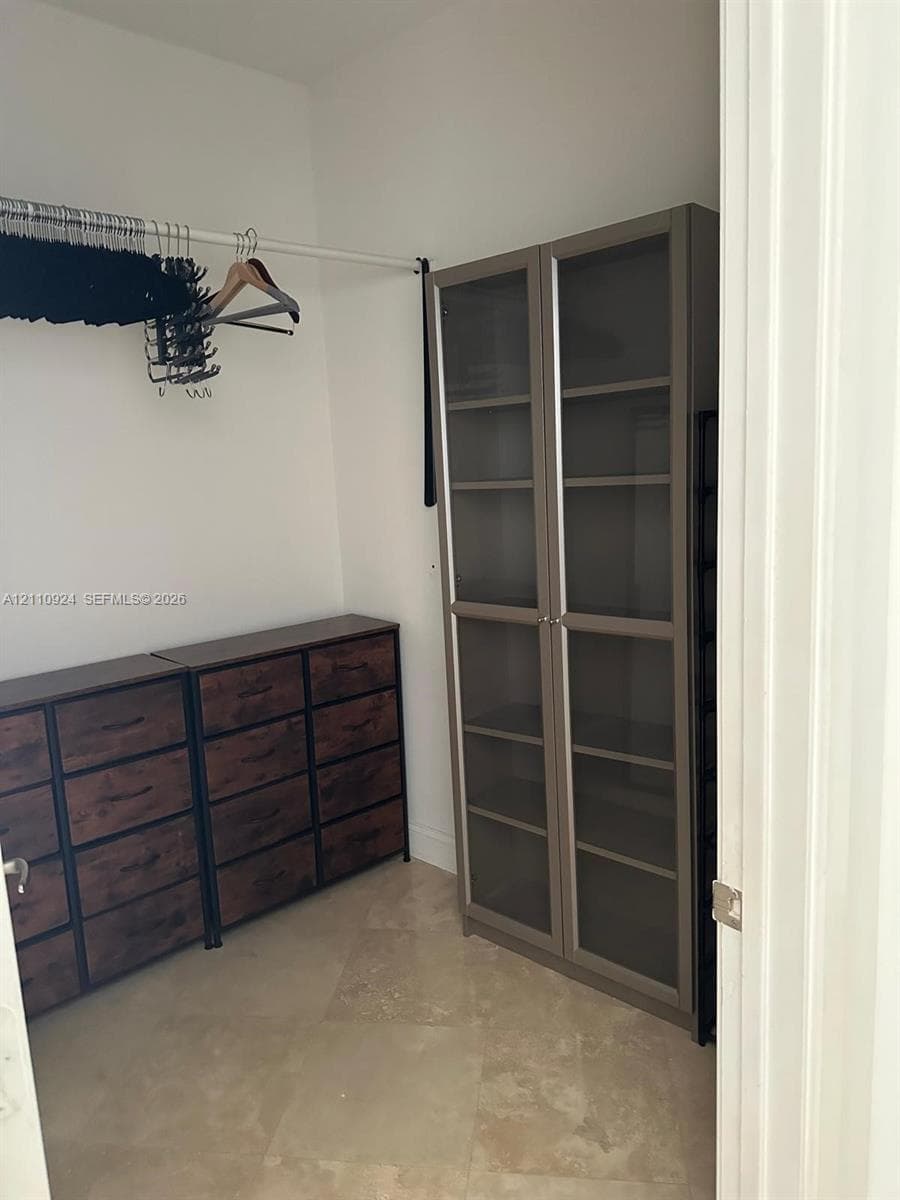 Storage space featuring tile flooring and a horizontal hanging rod