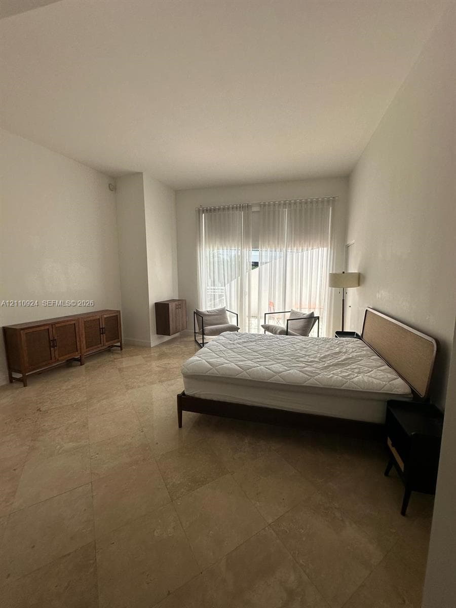 Room with stone tile flooring, high ceilings, and large glass sliding doors featuring floor-to-ceiling vertical blinds