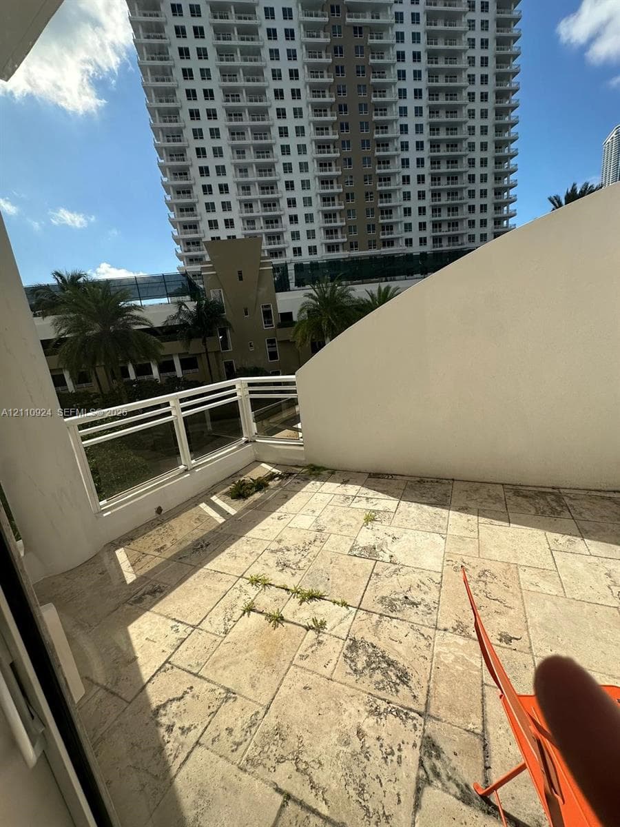 Private balcony featuring stone-tile flooring and a white metal railing
