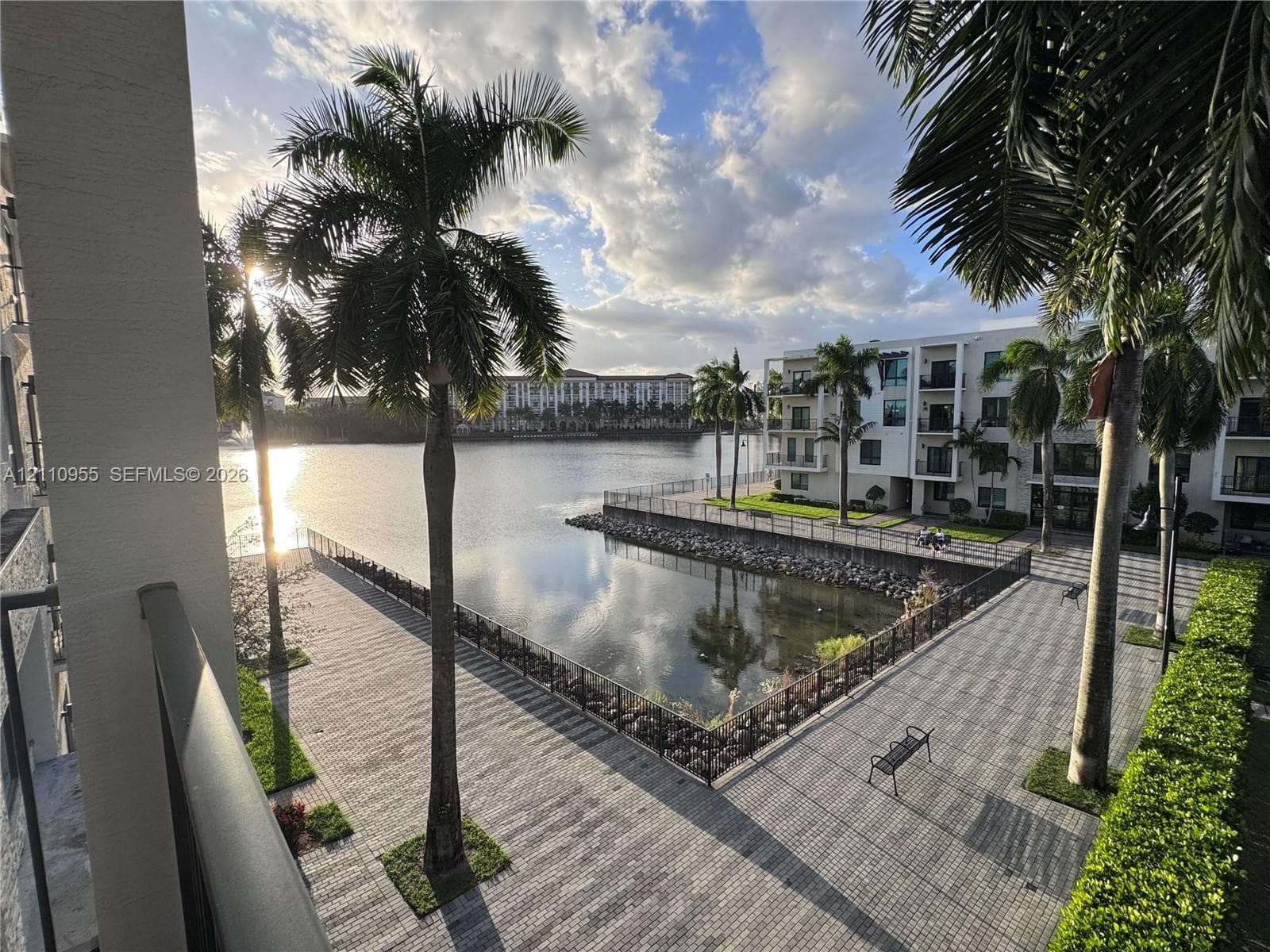 Waterfront terrace featuring paved walkways, integrated metal railings, mature palm trees, and bulkhead stone detailing
