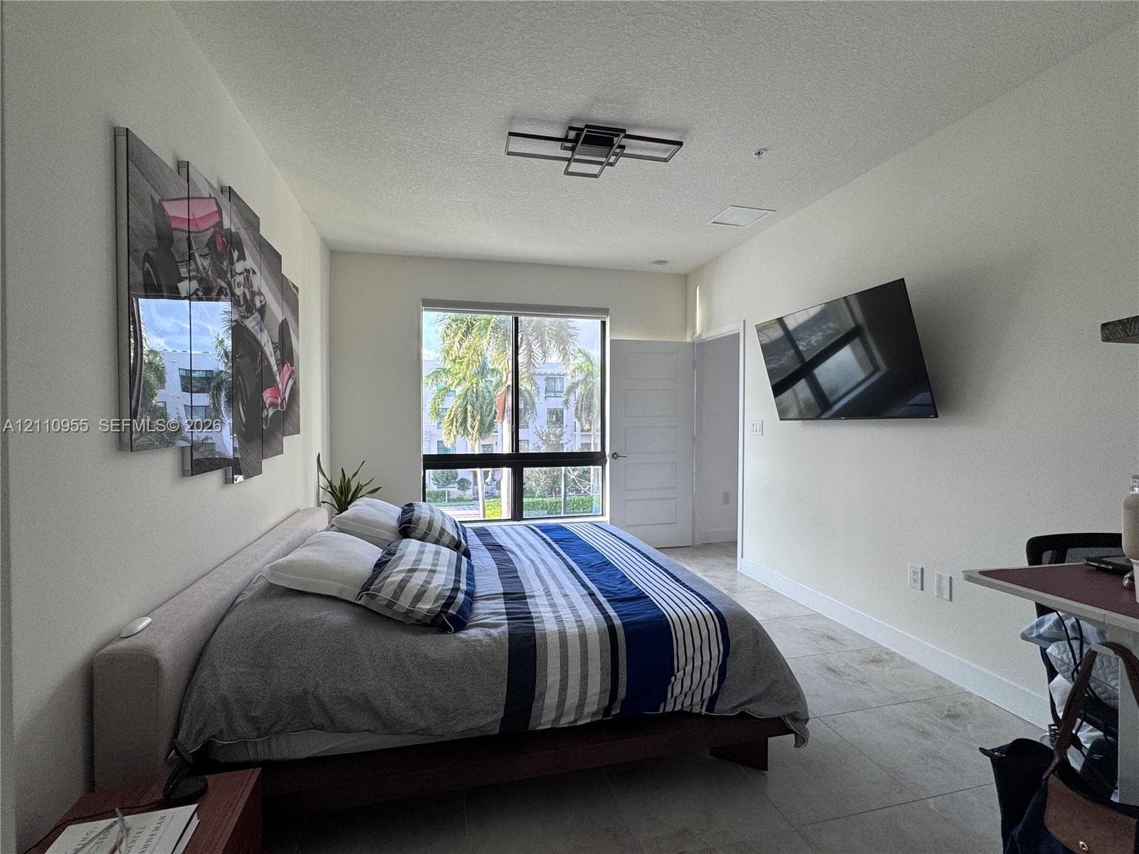 Large format tile flooring, contemporary geometric ceiling light fixture, and floor-to-ceiling window framing exterior landscape