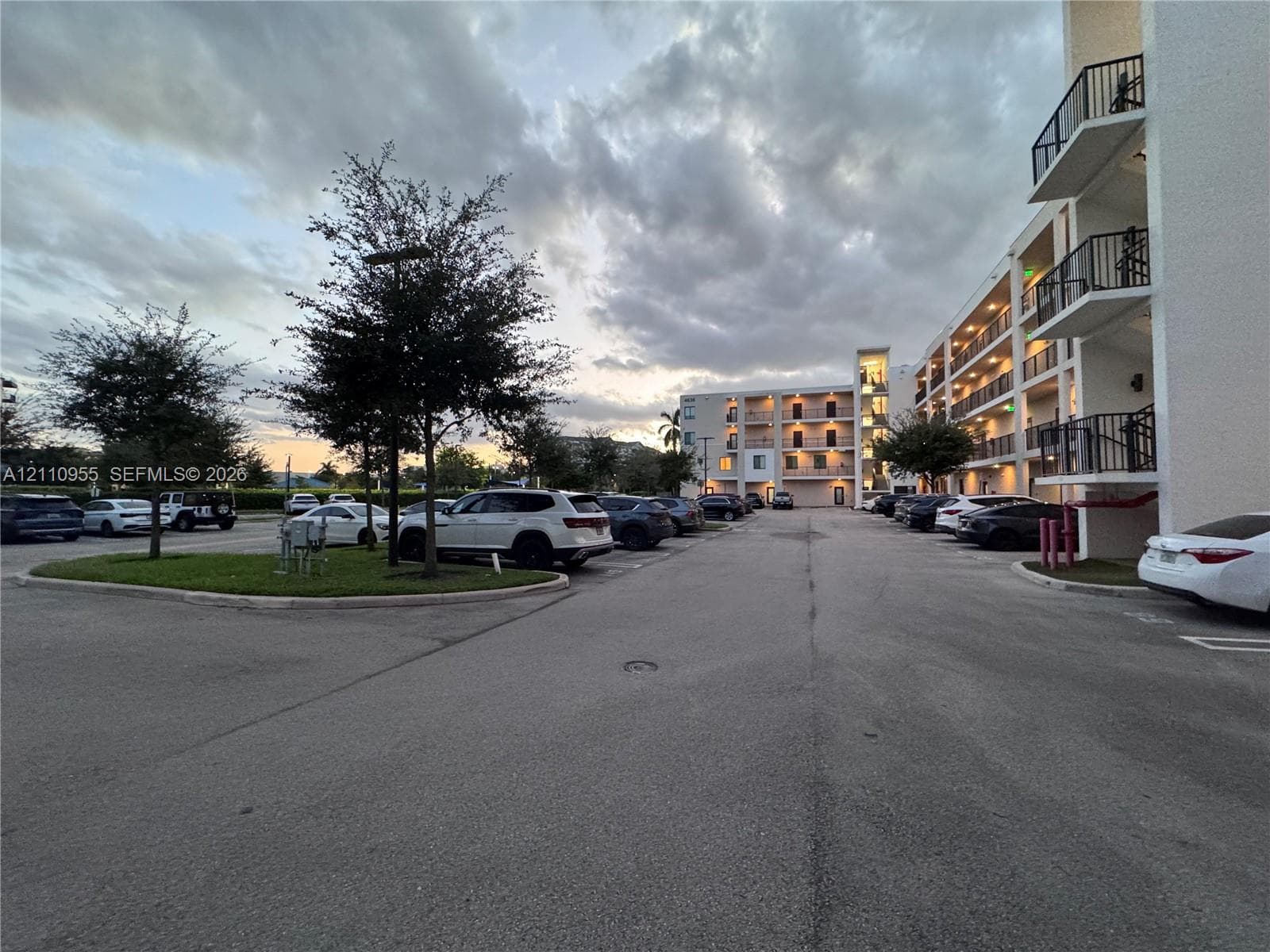 Multi-story residential complex featuring stucco exterior walls, private metal-railed balconies, and surface parking