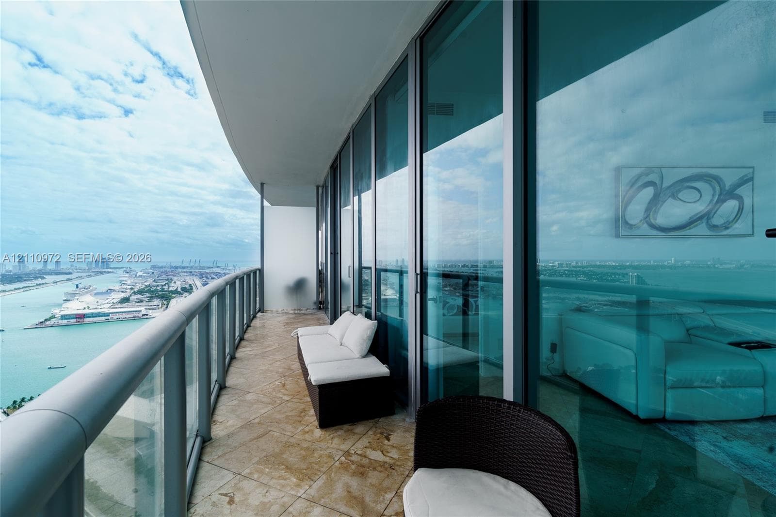 Curved balcony featuring floor-to-ceiling glass paneling, stone tile flooring, and a metal railing