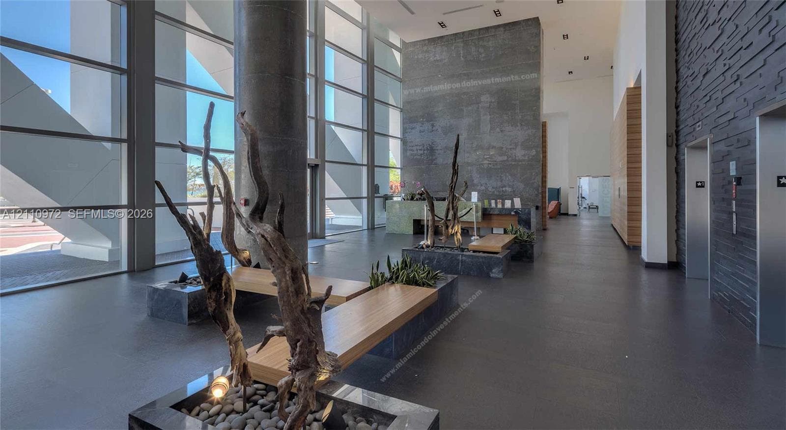 Fitness center featuring floor-to-ceiling windows, exposed industrial ductwork, linear pendant lighting, and rubberized flooring