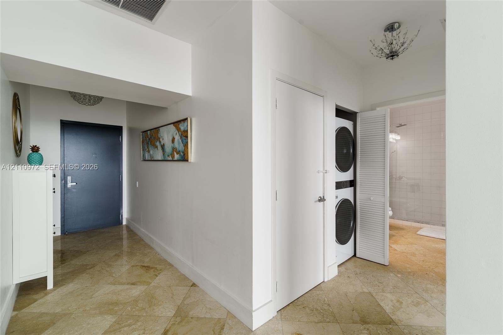 Stone-finish tile flooring, recessed ceiling lighting, louvered closet doors, and a stacked laundry unit
