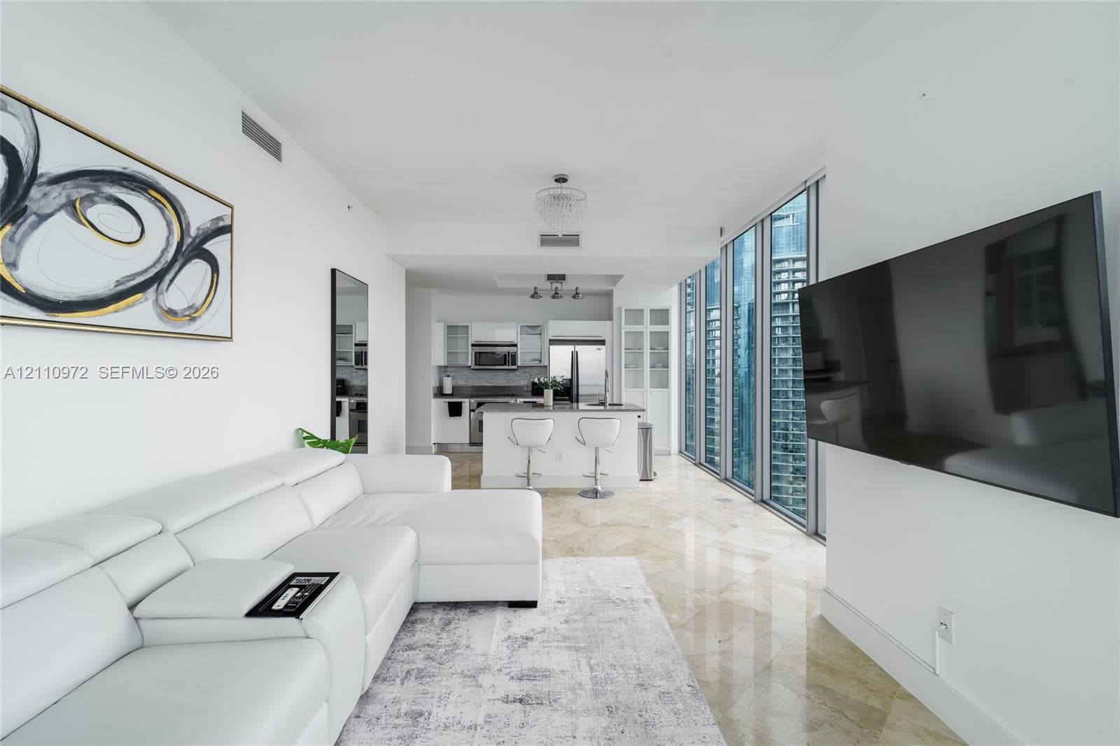 Polished stone flooring, floor-to-ceiling windows, modern kitchen with stainless steel appliances, and built-in glass cabinetry