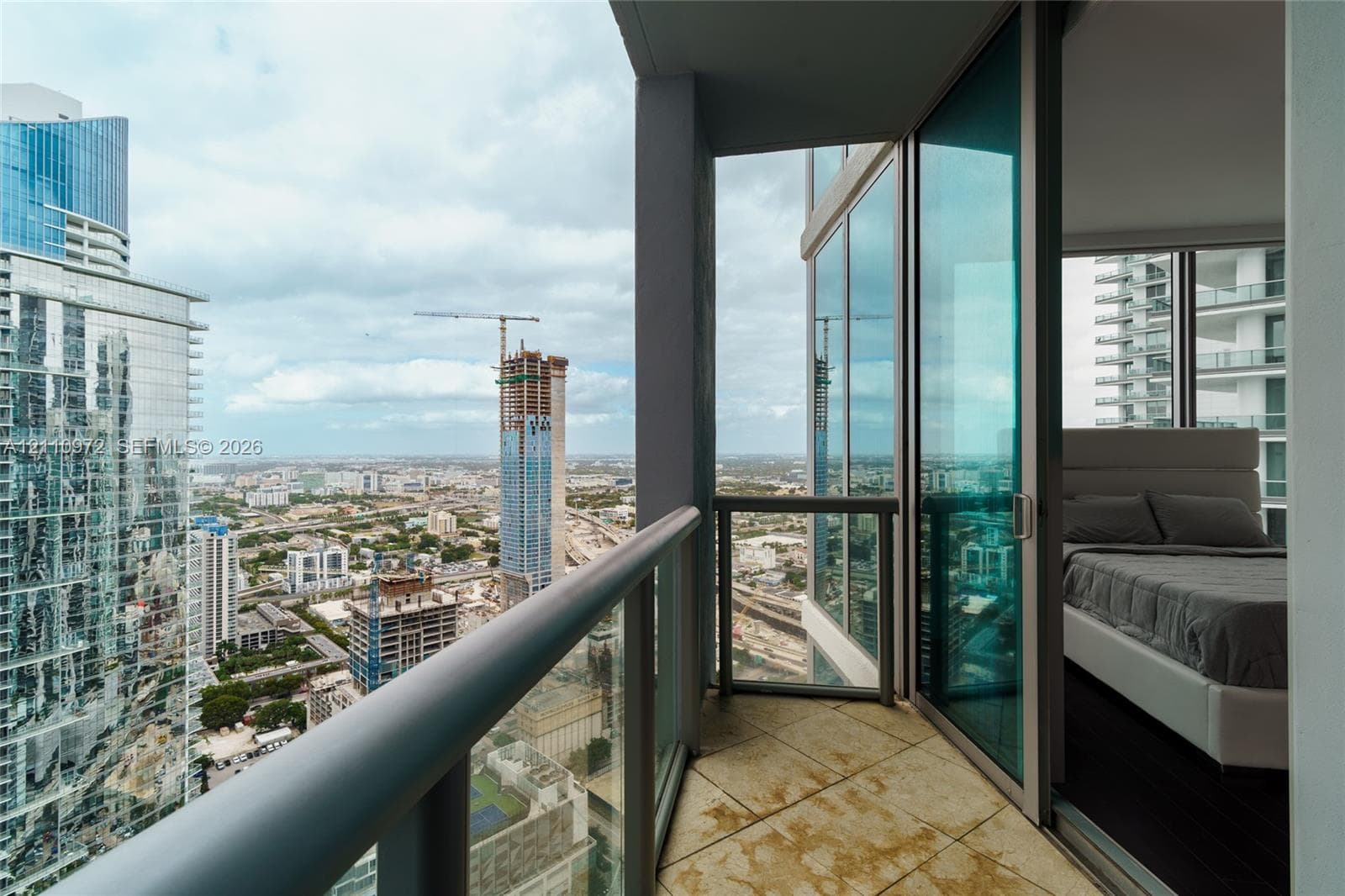 Covered balcony featuring tile flooring, metal railings, and floor-to-ceiling glass paneling