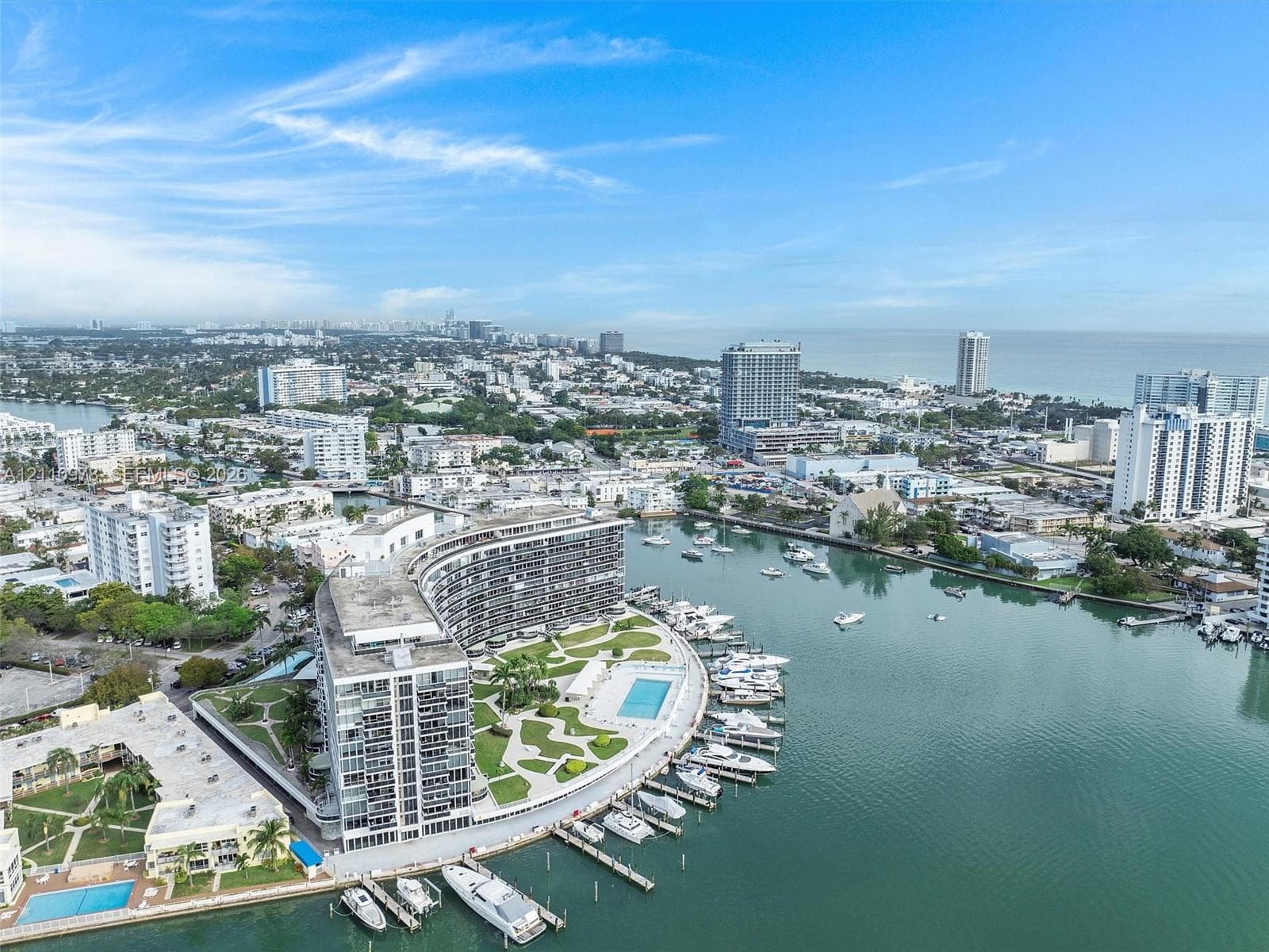Waterfront high-rise building featuring a private marina, paved outdoor recreation area, swimming pool, and landscaped grounds