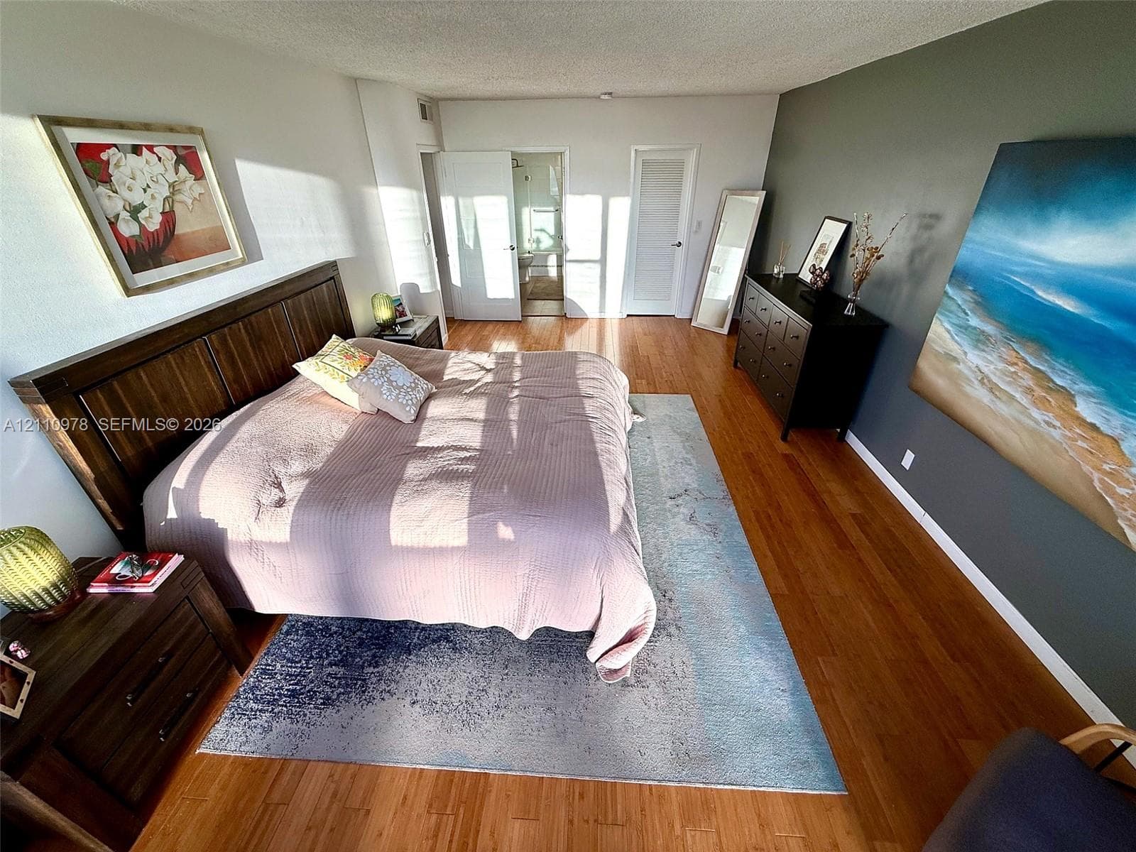 Spacious room featuring wood-finish flooring, a prominent accent wall, and double-door entry