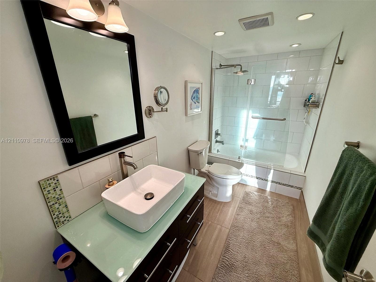 Vanity featuring a glass countertop, rectangular vessel sink, and dark cabinetry